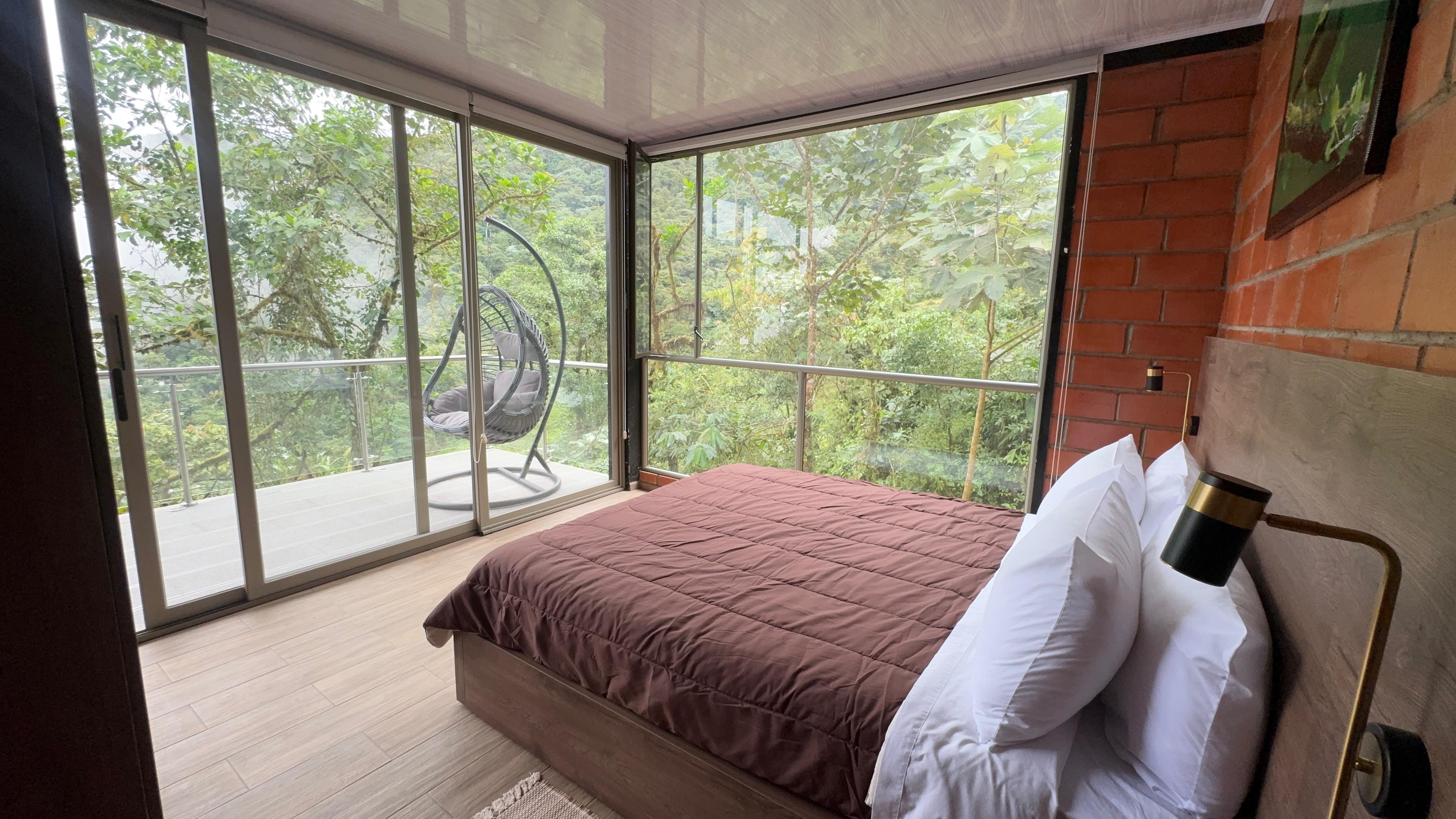 Bedroom with hanging chair and forest balcony, Mashpi cloud forest lodge